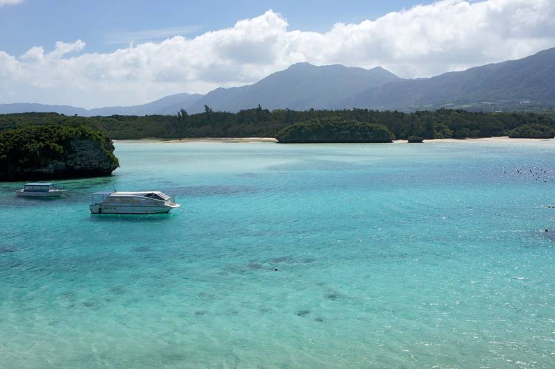 石垣島の川平湾、エメラルド色の浅い海に浮かぶ小島とボート