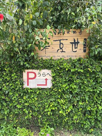 ツタに覆われた塀に掛かる来夏世の木の看板
